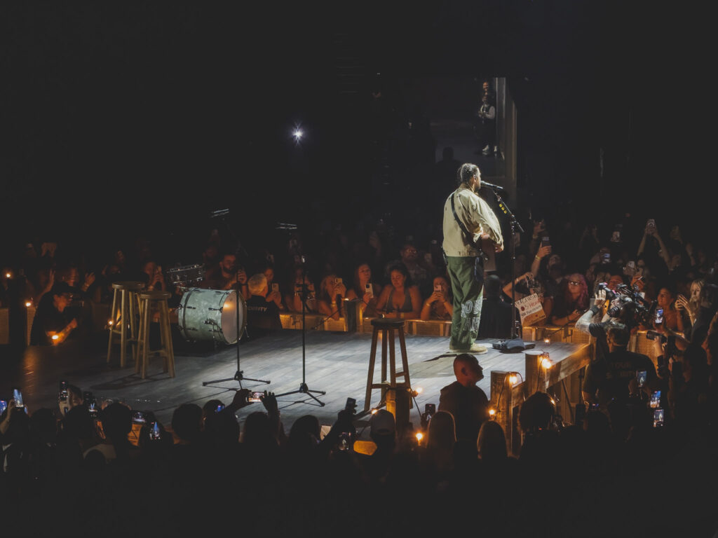 Noah Kahan performing on a candle-lit B-stage in the round, Orlando
