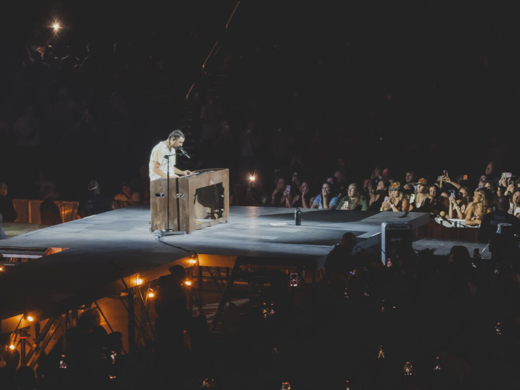 Noah Kahan at a wooden upright piano on the satellite stage for "End of August", Orlando concert