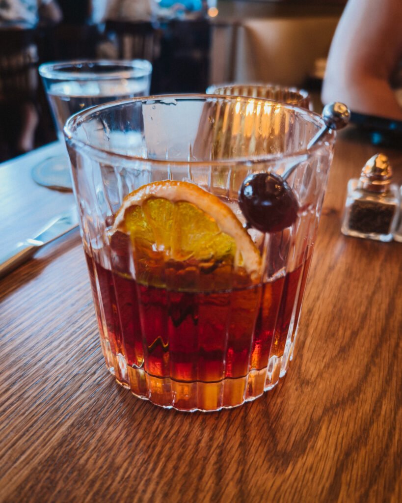 Allswell - Waterside Place Review 85 Smoked old fashioned cocktail at Allswell with an orange slice and cherry in a ribbed rocks glass
